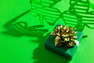 Image of green clover glasses with green present and copy space on green background © vectorfusionart