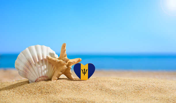 Beautiful beach in the Barbados. Flag of Barbados in the shape of a heart and shells on a sandy beach.