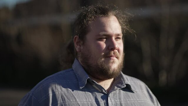 One Contemplative Young Chubby Man Walking Outdoors In Sunlight With Meditative Expression Walks Forward In Contemplation