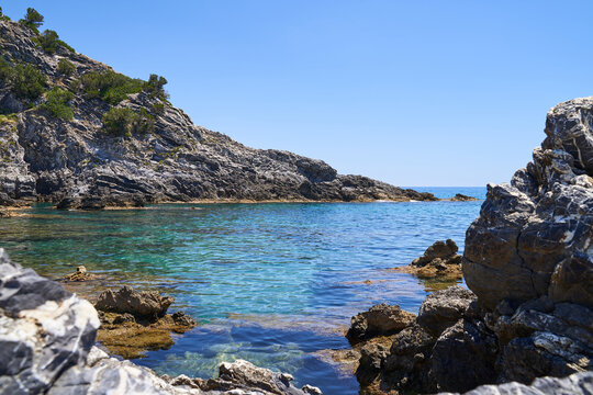 Stony rocks on Ascea beach in the Salerno region of southern Italy. The water of the sea is clear and has a turquoise color. The sky is blue and space for text.