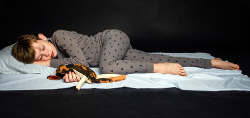 Youth Child Preteen Boy Sleeping in Pajamas with Toy and Pillow in Studio © 3Days2Go Media