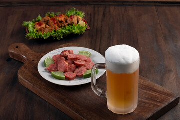 Beer mug on wooden board with portion of fried chicken and sausage