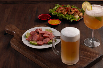 Beer mug on wooden board with portion of fried chicken and sausage