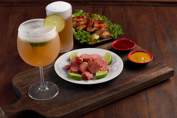 Beer mug on wooden board with portion of fried chicken and sausage