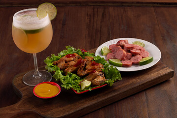 Beer mug on wooden board with portion of fried chicken and sausage