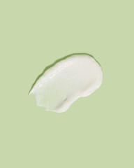 Beauty cream smear smudge on green background. Cosmetic skincare product texture. Face cream, body lotion swipe swatch