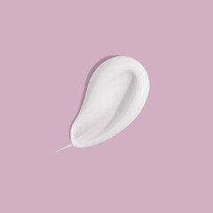 White beauty cream smear smudge on pink background. Cosmetic skincare product texture. Face cream, body lotion swipe swatch