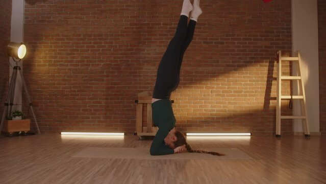 Yoga trainer doing handstand balancing on arms with legs up