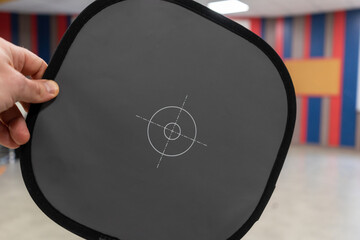 Gray card for determining the white balance for photo or video shooting in a male hand indoors.