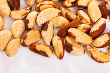 Healthy snack. Shelled roasted Brazil nut seeds on white surface..