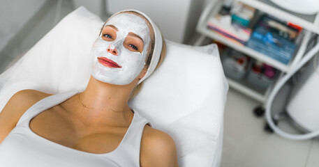 Beautiful White woman getting a white revitalising face beauty mask. High quality photo