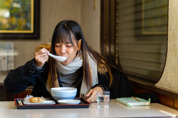 Young Asian woman tourist eating Japanese food breakfast rice ball with soup at local Japanese...