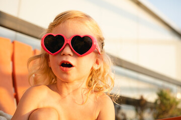 Caucasian baby girl, child, kid wearing ping heart form sun glasses, surprised, close up, lifestyle...
