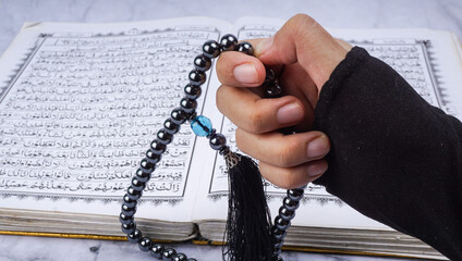 Islam holy book of Muslims, the Quran. Holy Al Quran and prayer beads or tasbih on marble background