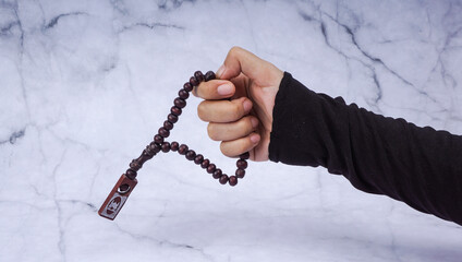 Selective focus image hand of muslim woman holding a prayer beads over marble background with copy space.