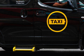 Black taxi with its yellow logo on the door.