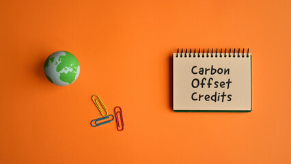 There is a notebook with the word Carbon Offset Credits. It is eye-catching image.