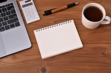 There is a wooden desk with a laptop, calculator, coffee, pen, and a sketchbook for title composition.