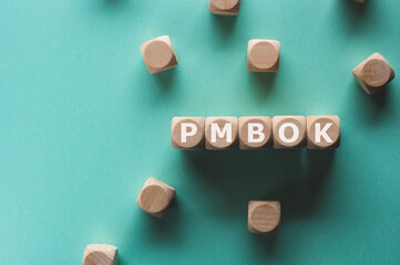 There is wood cubes with the word PMBOK. It is an acronym for Project Management Body of Knowledge...