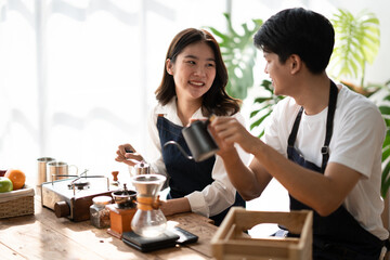 Young smiling couple in love spending a weekend morning together while making coffee at the kitchen, having breakfast together.