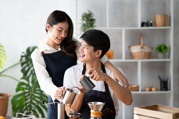 Young smiling couple in love spending a weekend morning together while making coffee at the kitchen, having breakfast together.