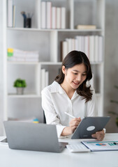 Young smart businesswoman writing her ideas on digital tablet while sitting in the modern office...
