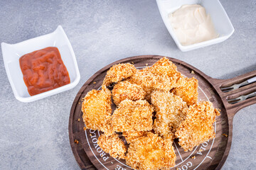 Delicious fried chicken on a rustic wooden board with tomato sauce and mayonnaise on a marbled background. Perspective view