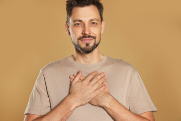 Man with clasped hands praying on beige background