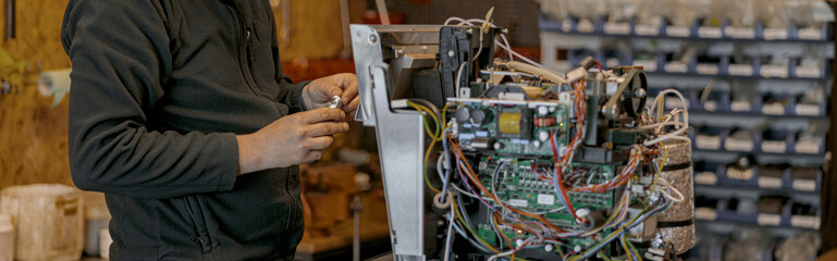 Male electrician repairing coffee machine in workshop
