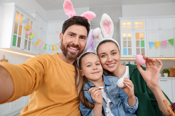 Happy family making selfie while painting Easter eggs in kitchen