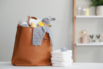 Mother's bag with baby's stuff on white wooden table indoors. Space for text