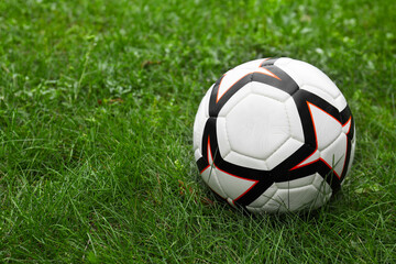Plakat New soccer ball on fresh green grass outdoors, space for text