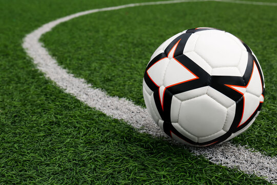 Soccer ball on green football field, space for text