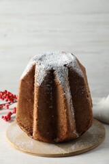 Delicious Pandoro cake decorated with powdered sugar on white wooden table. Traditional Italian pastry