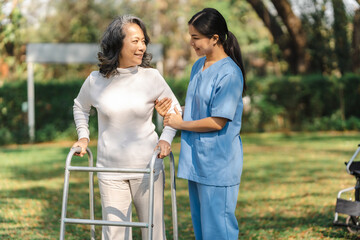 Young asian care helper with asia elderly woman on wheelchair relax together park outdoors to help and encourage and rest your mind with green nature. Help support yourself to learn to walk. walker