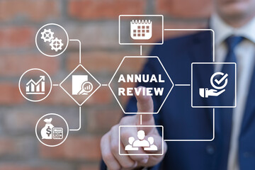 Businessman using virtual touchscreen presses inscription: ANNUAL REVIEW. Concept of annual review,...