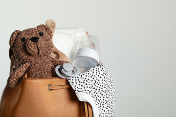 Mother's bag with baby's stuff on light grey background. Space for text