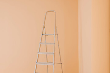 Ladder near pale orange wall. Room renovation