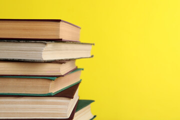 Stack of old hardcover books on yellow background, closeup. Space for text