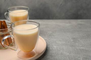 Delicious eggnog with cinnamon on light grey table. Space for text