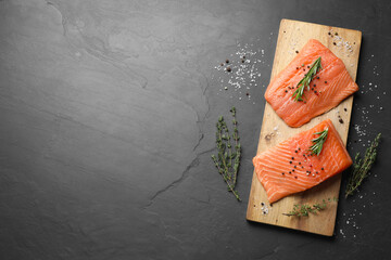 Fresh raw salmon and spices on black table, flat lay. Space for text