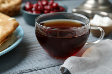 Glass cup of aromatic tea on light blue wooden table, closeup