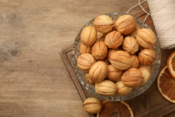 Bowl of delicious nut shaped cookies and dried orange slices on wooden table, flat lay. Space for text