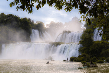 Fishermen at the charming Ban Gioc waterfall on paddling boat. The huge waterfall is on the border line of Vietnam and China.