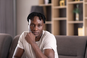 Portrait of young african man sitting and looking to camera at home