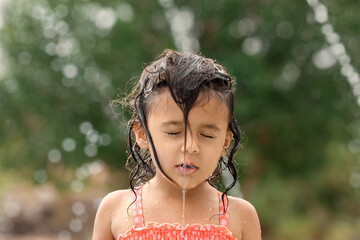 Little toddler girl standing with wet hair at playground in the summer, childhood memories and kids...
