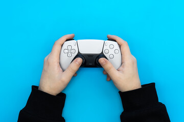 A male hands hold a gamepad on a blue background. Concept of the game, e-sports, leisure, gaming industry, video games, top view. © sav_an_dreas
