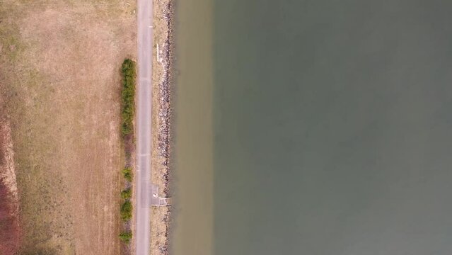 Drone flies in bird's eye view along the brown - green banks of the Danube