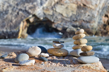 Stacked Stones on a Rocky Beach In Front of a Big Hollow Rock