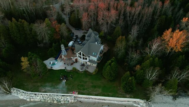 aerial of a blue vacation home from wisconsin USA filmed on autumn. private lighthouse sorounded by green trees.